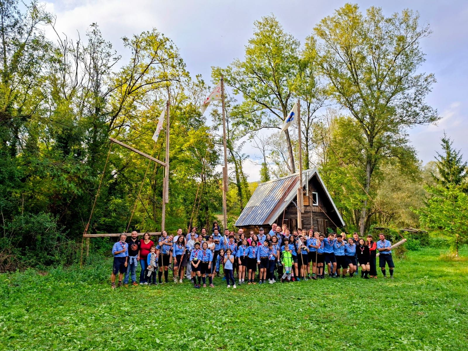 Foto di gruppo del Piacenza 2 in uniforme davanti a una baita nel bosco, con le bandiere sui pennoni